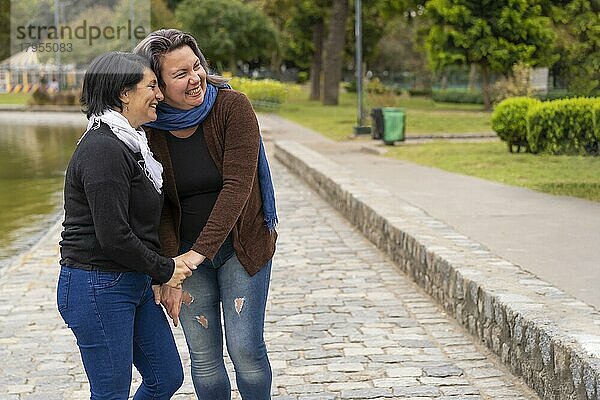 Lesbisches Paar in einem Park  das sich lachend an den Händen hält  Textfreiraum