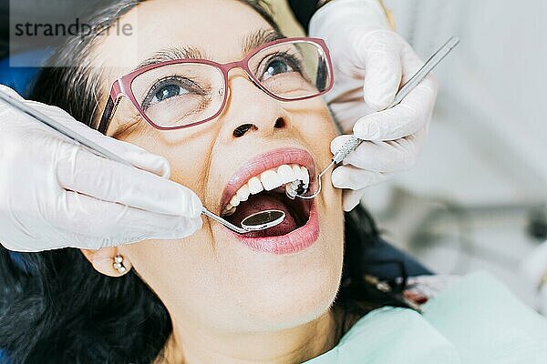 Vom Zahnarzt untersuchter Patient  Nahaufnahme eines Zahnarztes mit einem Patienten  Zahnarzt führt eine Wurzelbehandlung an einem Patienten durch  Zahnarzt führt eine zahnärztliche Untersuchung durch