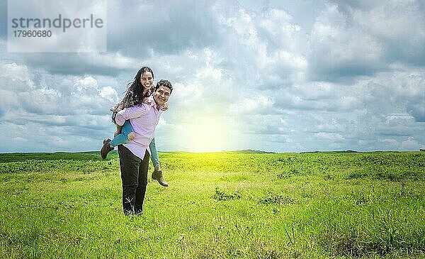 Glückliches verliebtes Paar auf dem Feld  glücklicher Mann trägt seine Freundin auf dem Feld