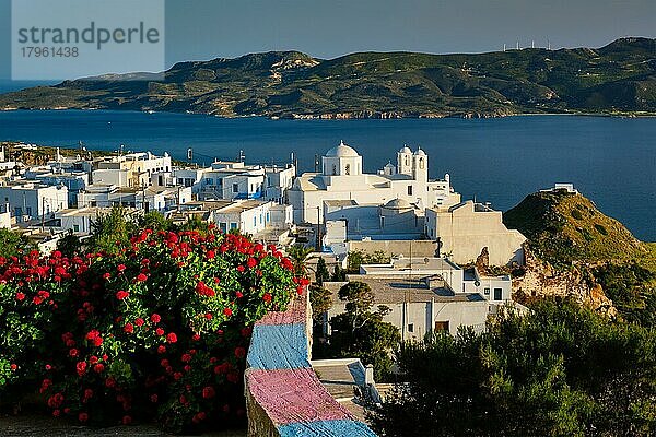 Malerischer Blick auf die griechische Stadt Plaka auf der Insel Milos über rote Geranienblüten und die orthodoxe griechische Kirche  Fokus Gebäude  Dorf Plaka  Insel Milos  Griechenland  Europa