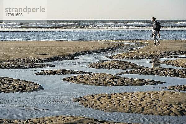 Spaziergängerin am Strand bei Ebbe mit Gezeitentümpeln  Insel Juist  Niedersächsisches Wattenmeer  Nordsee  Ostfriesland  Niedersachsen  Deutschland  Europa