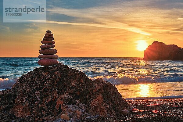 Konzept des Gleichgewichts und der Harmonie  Steinhaufen Kieselsteinhaufen am Strand Küste des Meeres in der Natur bei Sonnenuntergang  Meditative Kunst des Steinstapelns