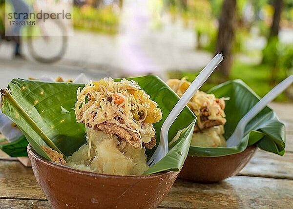 Vigorón mit Blättern serviert auf einem Holztisch  zwei Vigorones serviert auf hölzernem Hintergrund  Vigorón typisches Essen aus Nicaragua