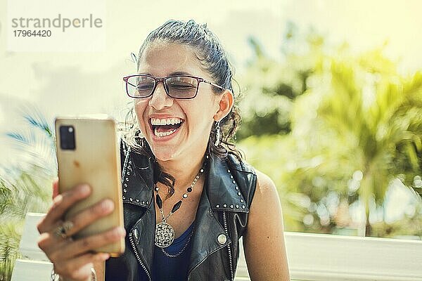 Nahaufnahme eines glücklichen Mädchens  das sein Handy überprüft  Glückliche Frau  die mit ihrem Handy im Freien sitzt  Handy  die auf einer Bank sitzt und eine Textnachricht sendet