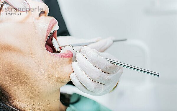 Zahnarzt bei der Kontrolle des Mundes eines Patienten  Nahaufnahme eines vom Zahnarzt kontrollierten Patienten  Nahaufnahme der Hände des Zahnarztes bei der Kontrolle des Mundes eines Patienten  Zahnarzt bei der Stomatologie