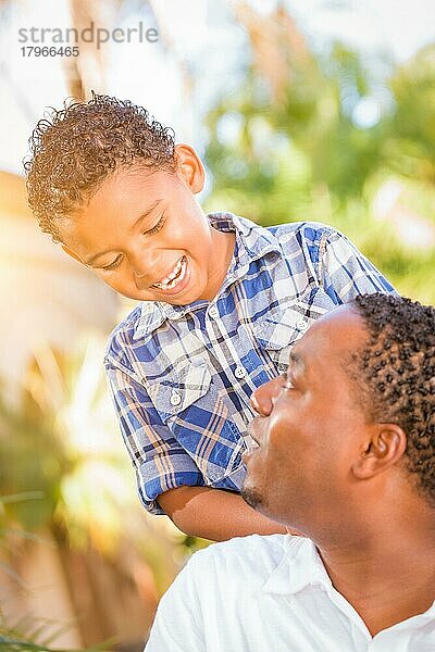 Gemischtrassiger sohn und afroamerikanischer vater spielen zusammen im freien