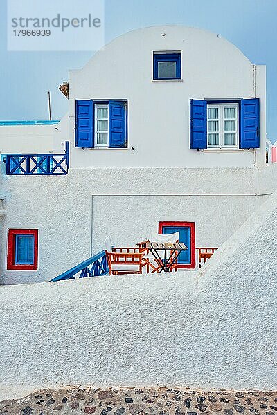 Traditionelles griechisches weiß getünchtes Haus mit blauen Türen und Fensterläden im Dorf Oia auf der Insel Santorin in Griechenland