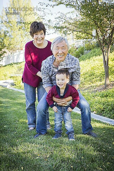 Happy chinese grandparents having fun with their mixed-race grandson outside