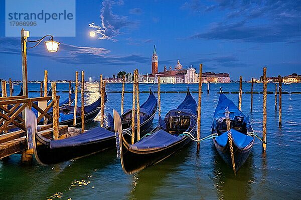 Romantischer Urlaub Venedig Reise Hintergrund  Gondeln am Markusplatz und Basilika San Giorgio Maggiore Kirche über Venedig Lagune mit Vollmond gesehen. Venedig  Italien  Europa
