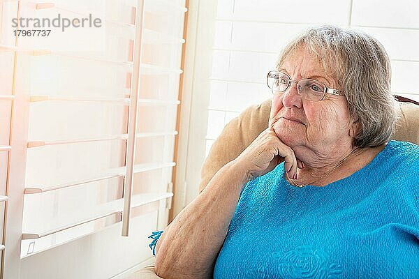 Nachdenkliche ältere Frau mit Blick aus dem Fenster