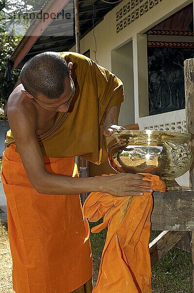 Buddhistischer Mönch putzt reinigt goldene Opferschale in buddhistisches Kloster  Insel Koh Lanta  Thailand  Asien