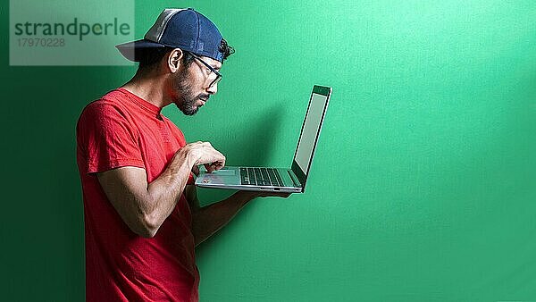 Kerl mit Mütze überprüft seinen Laptop isoliert  überraschter Mann überprüft seinen Laptop