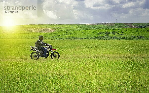 Biker Mann auf einer Landstraße  junger Mann auf seinem Motorrad unterwegs durch die Landschaft mit Kopie Raum  Mann fährt Motorrad auf dem Lande