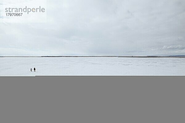 Zwei Menschen stehen auf einer weiten  zugefrorenen Flusslandschaft  Sankt-Lorenz-Strom  Provinz Quebec  Kanada  Nordamerika