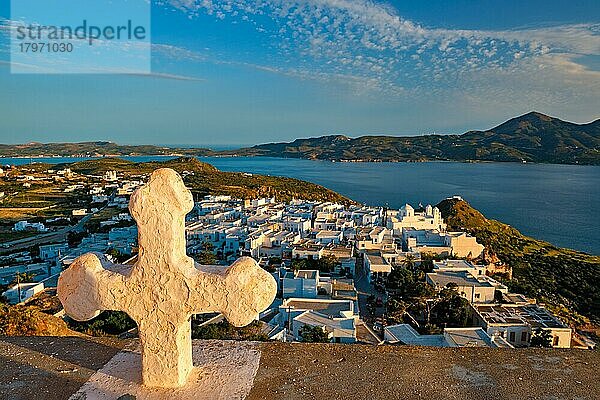 Griechisch-Orthodoxes Christentum Konzept Hintergrund  Fokus Blumen  christliche Kreuz mit Plaka Dorf auf Milos Insel im Hintergrund auf Sonnenuntergang  Plaka Stadt  Milos Insel  Griechenland  Europa