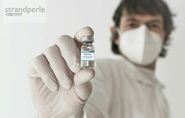 Arzt mit Impfstoffflasche und Spritze  Beginn der weltweiten Massenimpfung gegen das Coronavirus COVID-19  Influenza oder Grippe  Welt-Immunisierungskonzept. Selektiver Fokus