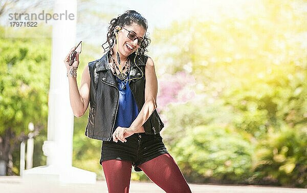 Latin girl listening to music outside  Urban girl enjoying music with headphones  Happy woman listening to music outside