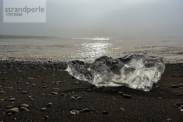 Geschmolzener Eisberg  Eiskristall am schwarzen Lavastrand  von der Morgensonne angestrahlt  Gegenlicht  Diamond Beach im Sommer  Dunst  Jökulsárlón  Vatnajökull Nationalpark  Island  Europa