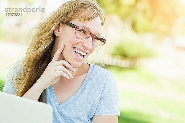Junge erwachsene Frau mit Brille im Freien  die ihren Laptop benutzt