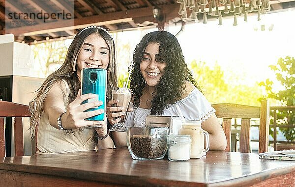Zwei Mädchen machen ein Selfie und trinken Kaffee  zwei Freundinnen in einem Café machen ein Selfie