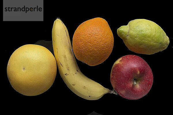 Verschiedene Obstsorten  Banane  Zitrone  Apfel  Apfelsine und Pampelmuse  auf schwarzem Grund  Studioaufnahme