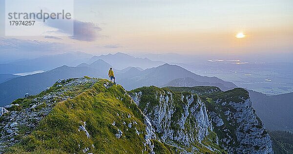 Wanderer am Gipfel der Benediktenwand bei Sonnenuntergang  hinten Silhouetten von Bergen  Bayerische Voralpen  Bayern  Deutschland  Europa