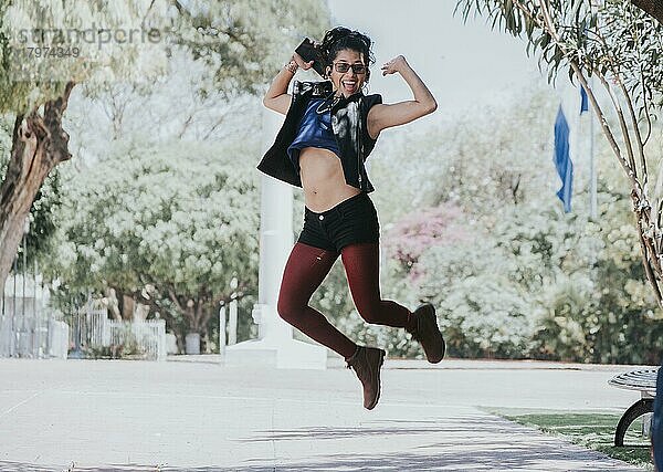 Happy urban girl jumping and listening to music  Girl jumping in the street and listening to music  Lifestyle girl listening to music  Woman jumping and enjoying music