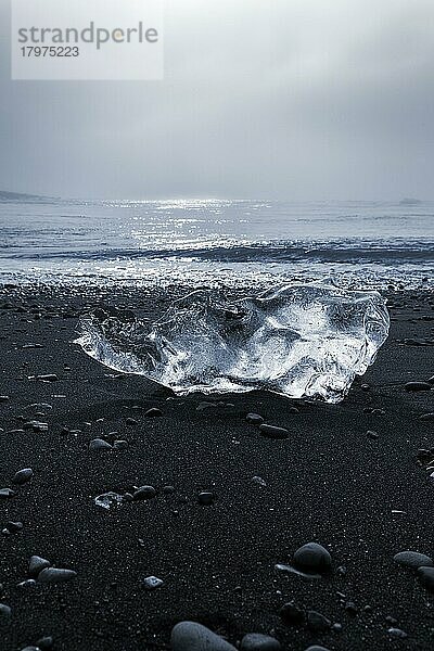 Geschmolzener Eisberg  Eiskristall am schwarzen Lavastrand  von der Morgensonne angestrahlt  Gegenlicht  Diamond Beach im Sommer  Dunst  Jökulsárlón  Vatnajökull Nationalpark  Island  Europa