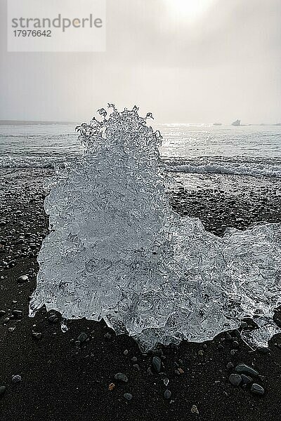 Geschmolzener Eisberg  Eiskristall am schwarzen Lavastrand  von der Morgensonne angestrahlt  Gegenlicht  Diamond Beach im Sommer  Dunst  Jökulsárlón  Vatnajökull Nationalpark  Island  Europa