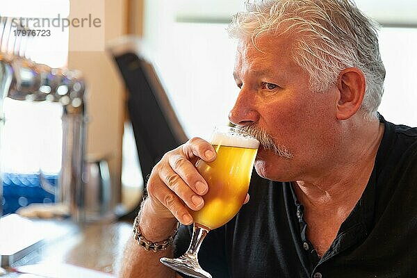 Gutaussehender Mann bei der Verkostung eines Glases Mikrobrauerei-Bier