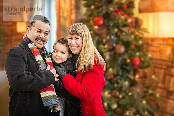 Junges gemischtrassiges Familienporträt vor einem Weihnachtsbaum in einem Haus