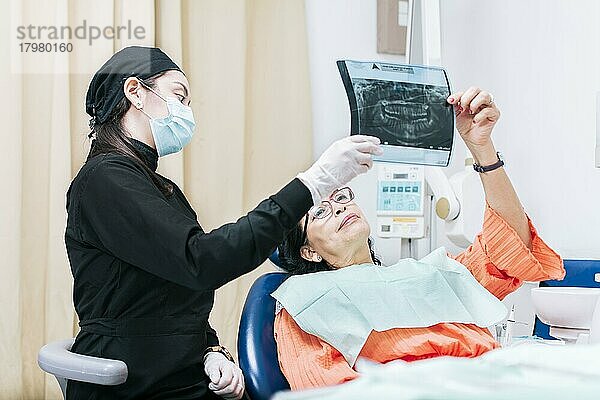 Zahnarzt zeigt Patientin Röntgenbild  Patientin betrachtet Röntgenbild mit Zahnarzt  Zahnpatientin hält ihr Röntgenbild  Zahnarzt mit Röntgenuntersuchung