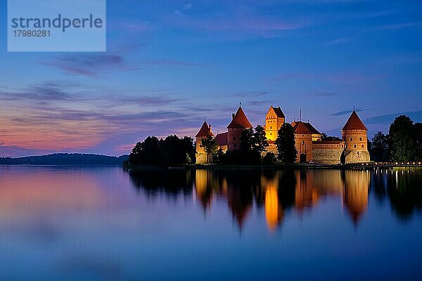 Nachtansicht der Burg der Insel Trakai im abendlich beleuchteten Galve-See  die sich im ruhigen Wasser spiegelt  Litauen  Europa