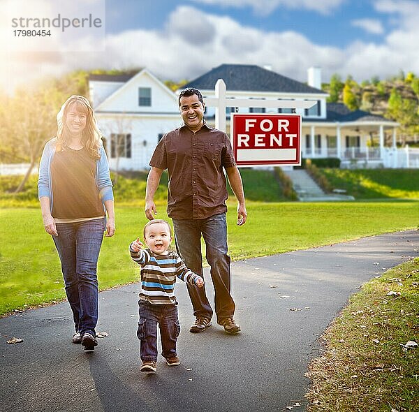 Glückliche gemischtrassige Familie  die vor einem Haus spazieren geht und ein Immobilienschild zu vermieten hat