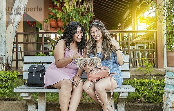 Zwei hübsche Mädchen lesen auf einer Bank  zwei hübsche Frauen lesen ein Buch auf einer Bank  Mädchen sitzen auf einer Bank und lesen