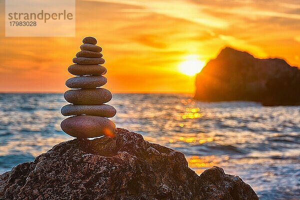 Konzept des Gleichgewichts und der Harmonie  Steinhaufen Kieselsteinhaufen am Strand Küste des Meeres in der Natur bei Sonnenuntergang  Meditative Kunst des Steinstapelns