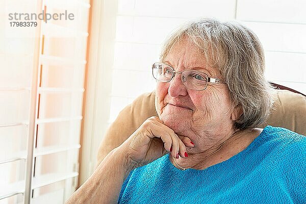 Zufriedene ältere Frau  die aus dem Fenster blickt