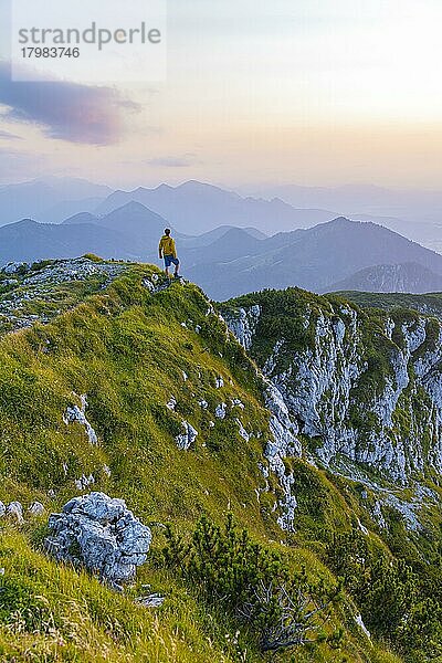 Wanderer am Gipfel der Benediktenwand bei Sonnenuntergang  hinten Silhouetten von Bergen  Bayerische Voralpen  Bayern  Deutschland  Europa