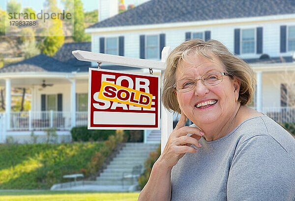 senior woman in front of sold home for sale real estate sign and beautiful house