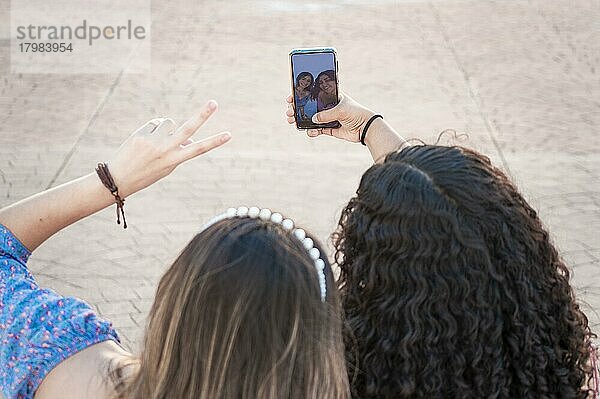 Zwei hübsche Mädchen nehmen ein Selfie  zwei lateinische Mädchen lächelnd und ein Selfie  weibliche Freundschaft Konzept