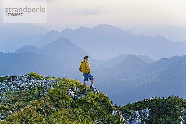 Wanderer am Gipfel der Benediktenwand bei Sonnenuntergang  hinten Silhouetten von Bergen  Bayerische Voralpen  Bayern  Deutschland  Europa