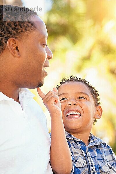 Gemischtrassiger sohn und afroamerikanischer vater spielen zusammen im freien