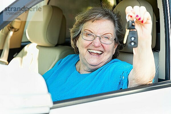 Glückliche ältere Frau  die in einem neuen Auto sitzt und die Schlüssel hält