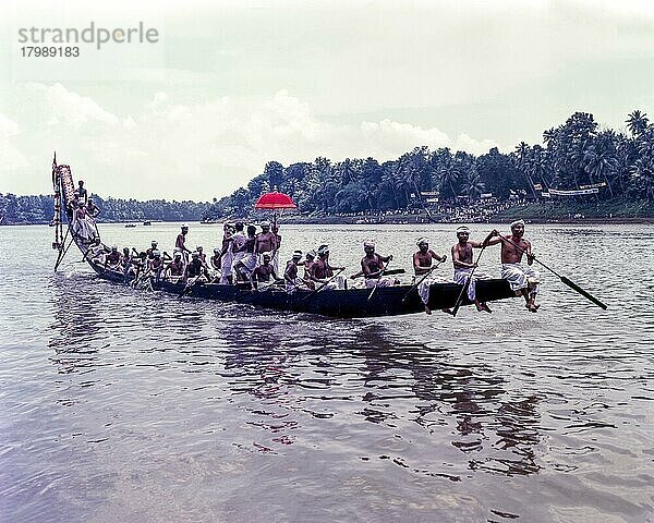 Die farbenfrohen Regenschirme  die von Männern in ihrer traditionellen Kleidung während des Aranmula-Bootrennens in den Booten mitgeführt werden  Kerala  Indien  Asien