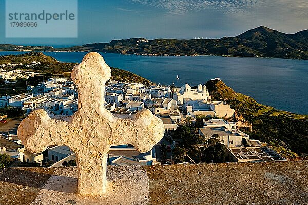 Griechisch-Orthodoxes Christentum Konzept Hintergrund  Fokus Blumen  christliche Kreuz mit Plaka Dorf auf Milos Insel im Hintergrund auf Sonnenuntergang  Plaka Stadt  Milos Insel  Griechenland  Europa