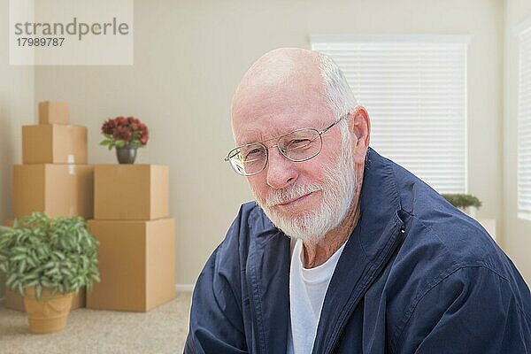 Älterer Mann in leerem Raum mit gepackten Umzugskartons