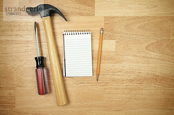 Papierblock  Bleistift  Hammer und Schraubenzieher auf einem Holzhintergrund