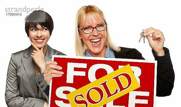Hispanic female behind with attractive blonde in front holding keys and sold for sale sign before a white background