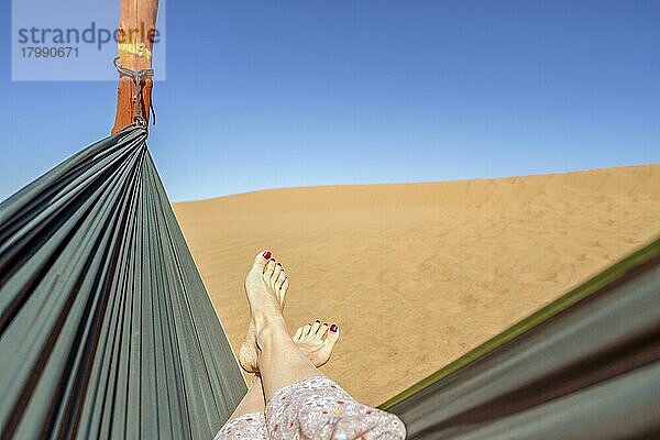 Junge Frau entspannt in grüner Hängematte mit Blick auf Sanddünen der Sahara-Wüste  Marokko  Afrika
