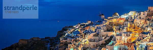 Panorama der berühmten griechischen ikonischen malerischen Reiseziel Oia Dorf mit traditionellen weißen Häusern und Windmühlen in Santorini Insel in den Abend blaue Stunde  Griechenland  Europa
